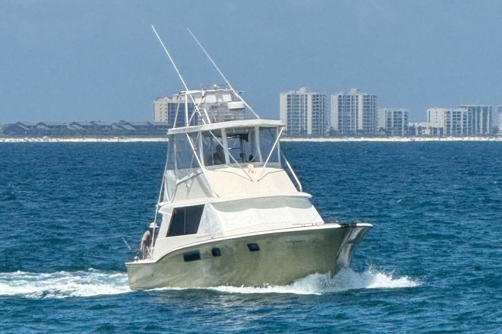 Boat cruising on ocean with city skyline in the background.
