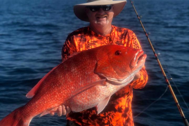 a man holding a fish on a boat in a body of water