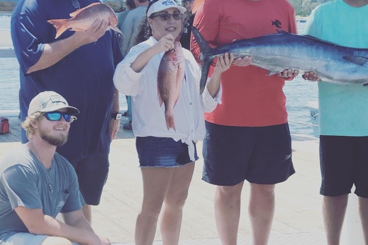 a group of people standing next to a person holding a fish