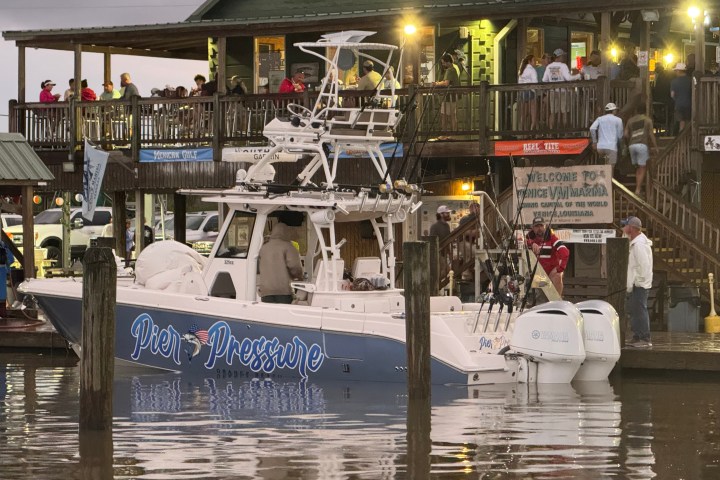 Boat named Pier Pressure docked at marina with people on a deck.